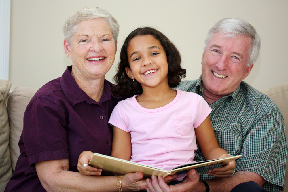 female adult, female child, male adult reading book and smiling